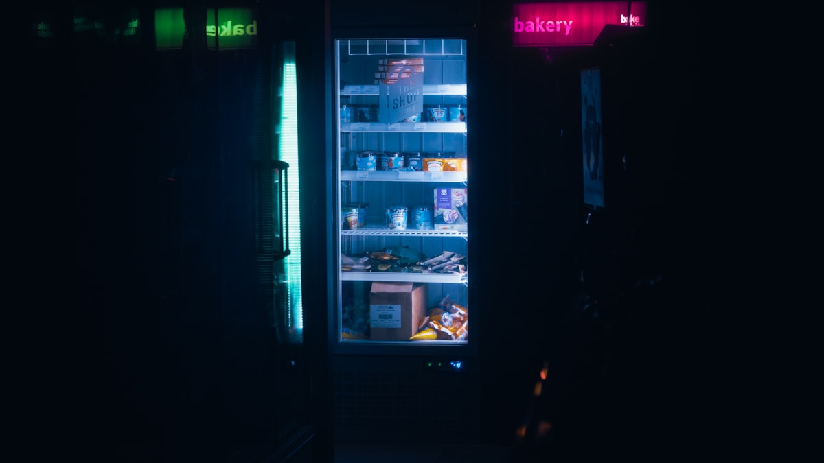 A glowing fridge in a dark shop at midnight
